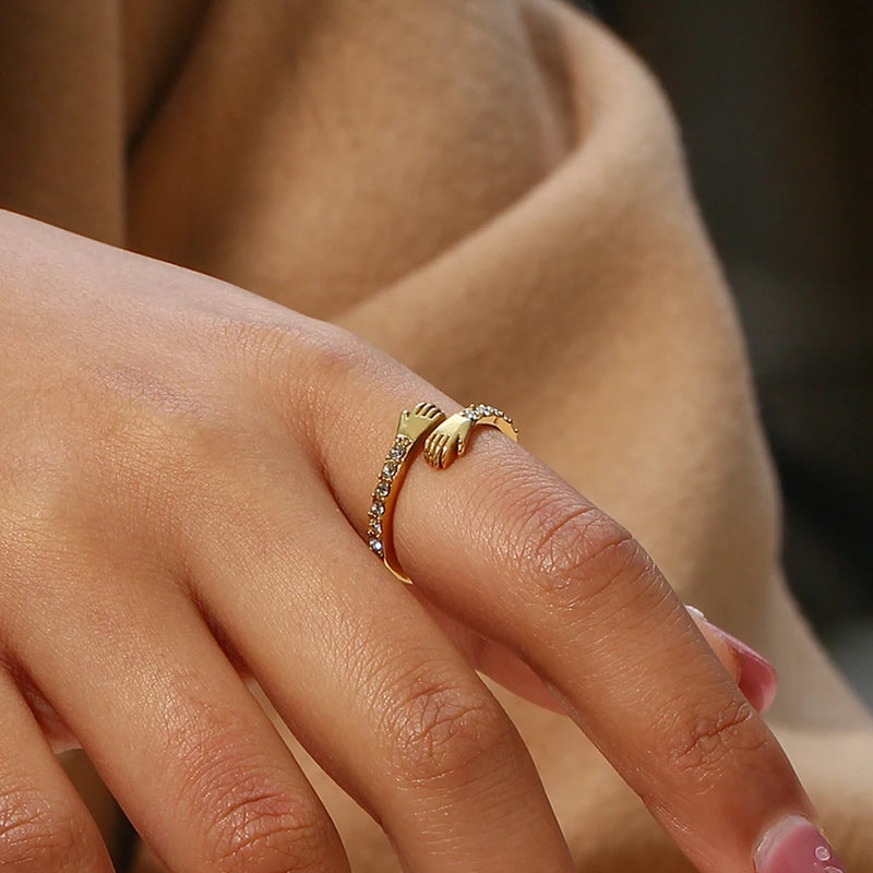 "Close-up of a hug ring with arms encircling, adorned with cubic zirconia stones, symbolizing love and connection."