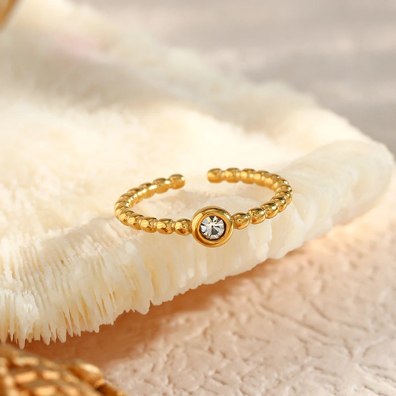 "Close-up of an adjustable ring with a bead-style band and a single sparkling crystal in the center, offering versatile elegance."