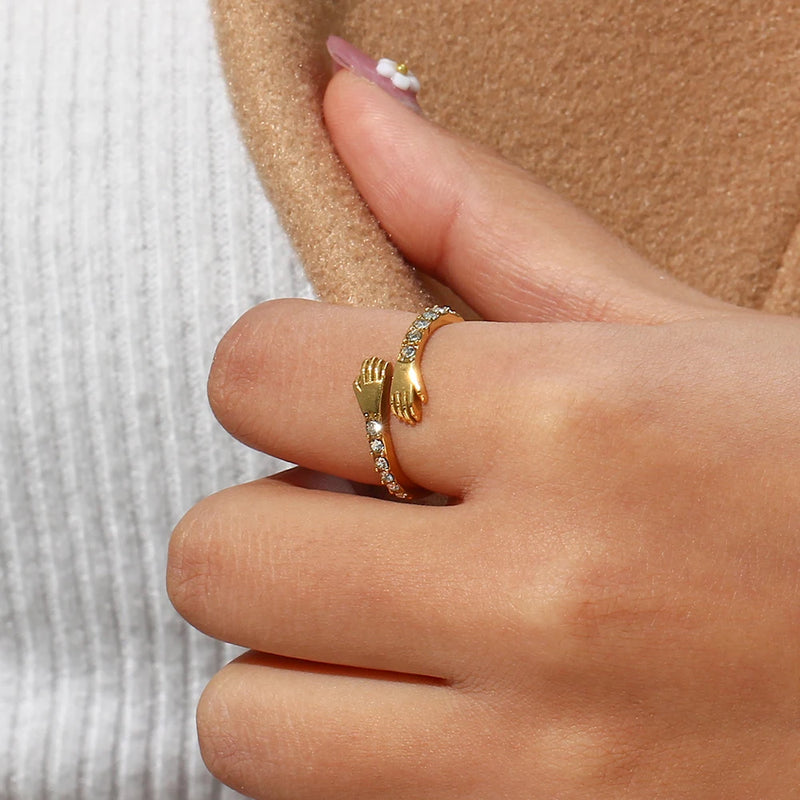 "Close-up of a hug ring with arms encircling, adorned with cubic zirconia stones, symbolizing love and connection."